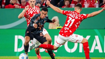 Jamal Musiala, hier beim Pokalspiel in Mainz, ist von den Gegenspielern kaum mit fairen Mitteln vom Ball zu trennen. (Foto: Torsten Silz/dpa)