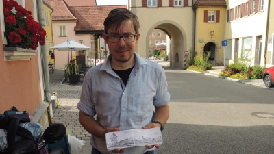 Mit seinem Fahrrad tourt der Kunsthistoriker derzeit durch die Region. Hier zeigt er seine Zeichnung von der Stadtbefestigung in Dinkelsbühl mit dem Bäuerlinsturm. (Foto: Peter Zumach)