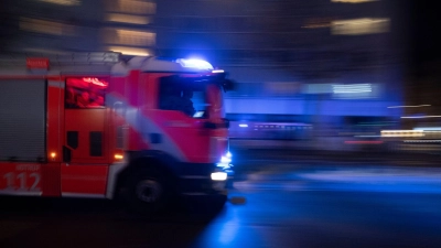 Feuerwehrleute löschen den Brand in einem Parkhaus. (Symbolbild) (Foto: Paul Zinken/dpa)