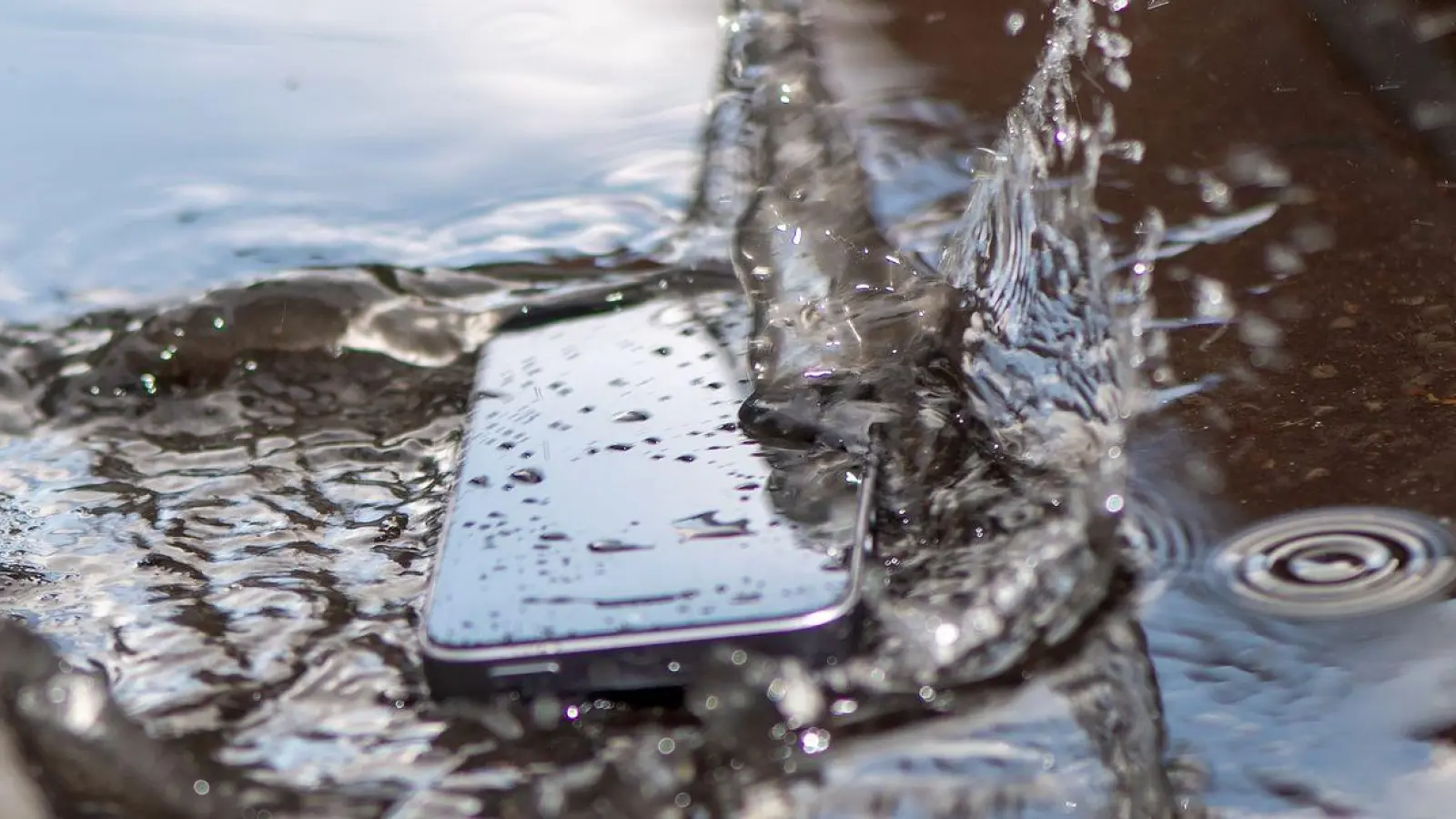 Auch gegen eindrigendes Wasser geschützte Smartphones überstehen ein solches Pfützenbad nicht automatisch ohne Schäden. (Foto: Zacharie Scheurer/dpa-tmn/dpa)