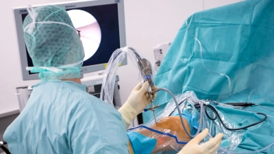 Ein Arzt operiert einen Patienten am Knie. (Foto: Sven Hoppe/dpa)