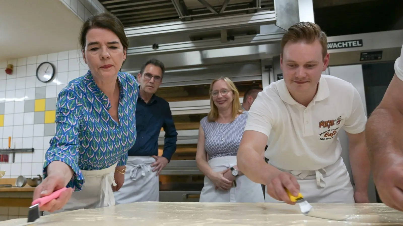 Tagesschau-Sprecherin Susanne Daubner (l) und Bäckermeister Vincent Richter von der Bäckerei Meye verteilen den Sulf-Belag auf dem weltgrößten Mohnkuchen. (Foto: Heiko Rebsch/dpa)