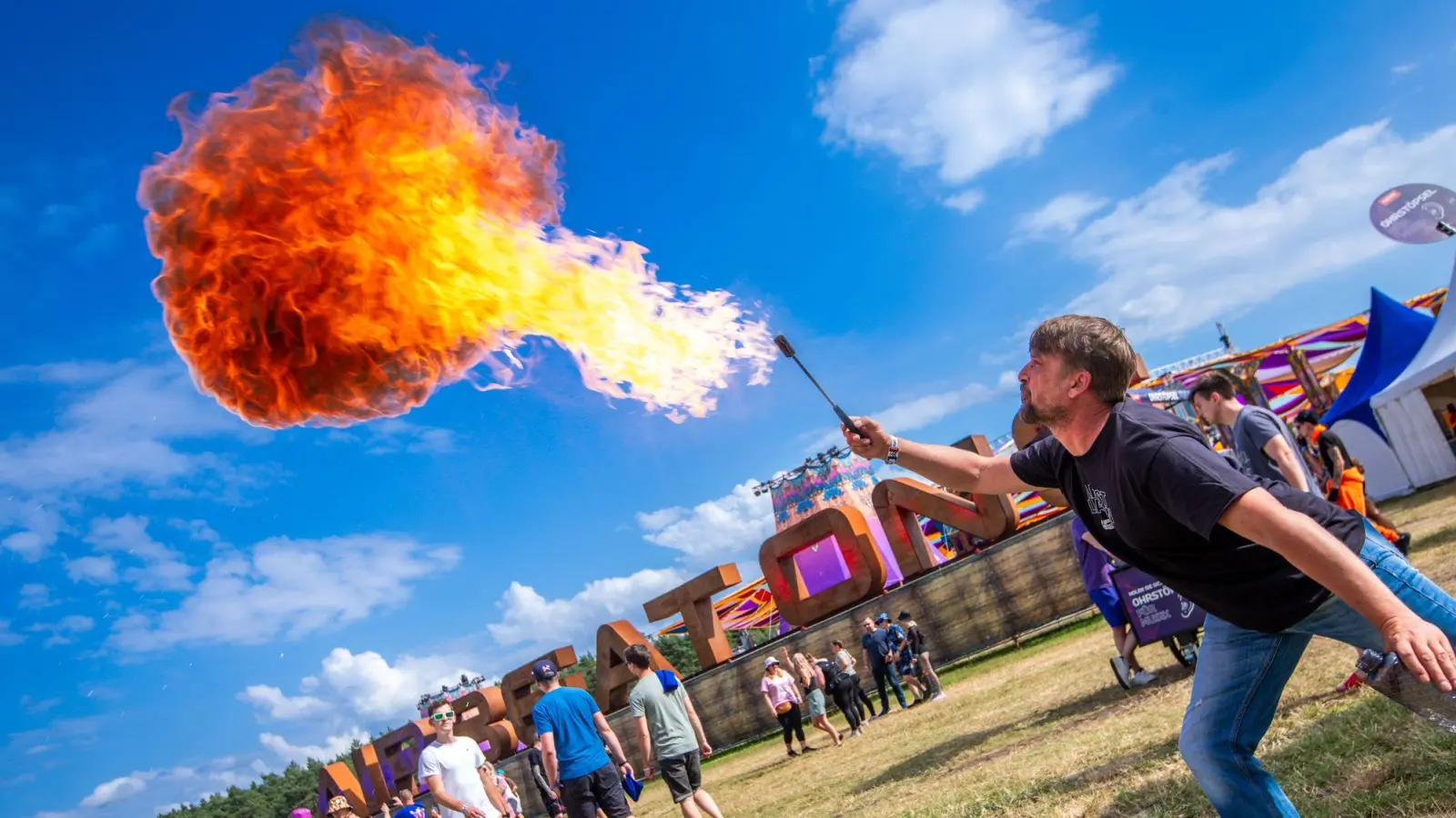 Ein Feuerspucker begrüßt am Eingang die ersten Besucher zum „Airbeat One“ Festival. (Foto: Jens Büttner/dpa)