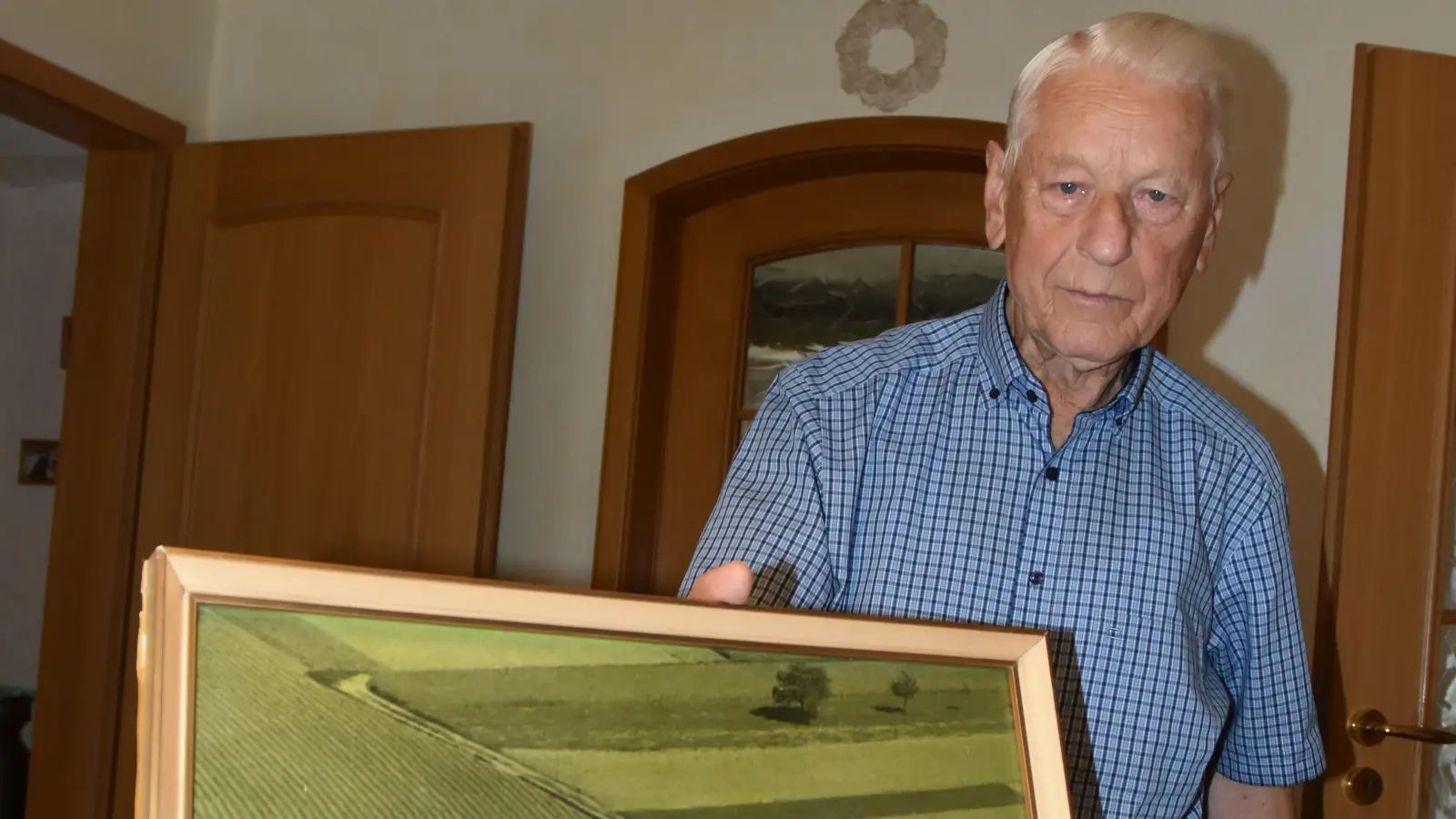 Der Instrumentenbauer Rudi Meinl senior mit einem Bild des Betriebes in der Blumenstraße 21 in Diespeck. Dies war seiner Erinnerung nach im Jahr 1961. Dort ist die Werkstatt heute noch. (Foto: Anita Dlugoß)