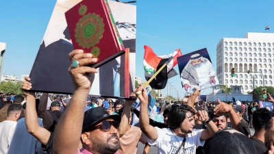 Anhänger des schiitischen Geistlichen Muqtada al-Sadr erheben den Koran, das heilige Buch der Muslime, während einer Demonstration vor der schwedischen Botschaft in Bagdad. (Foto: Hadi Mizban/AP/dpa)