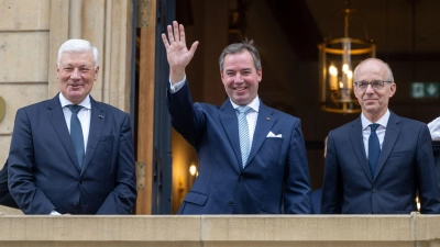 Prinz Guillaume (Mitte), Erbgroßherzog von Luxemburg, winkt nach seiner Ernennung zum „Lieutenant-Représentant“ (Ehrenleutenant) neben Luc Frieden (l), Premierminister von Luxemburg, und Jean-Claude Wiseler, Präsident des Abgeordnetenhauses, vom Balkon des Abgeordnetenhauses. (Foto: Harald Tittel/dpa)