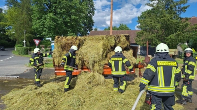 Feuerwehrleute sind in Birnbaum dabei, die brennenden Strohballen auseinander zu ziehen. (Foto: Kreisfeuerwehrverband Neustadt a.d. Aisch - Bad Windsheim)
