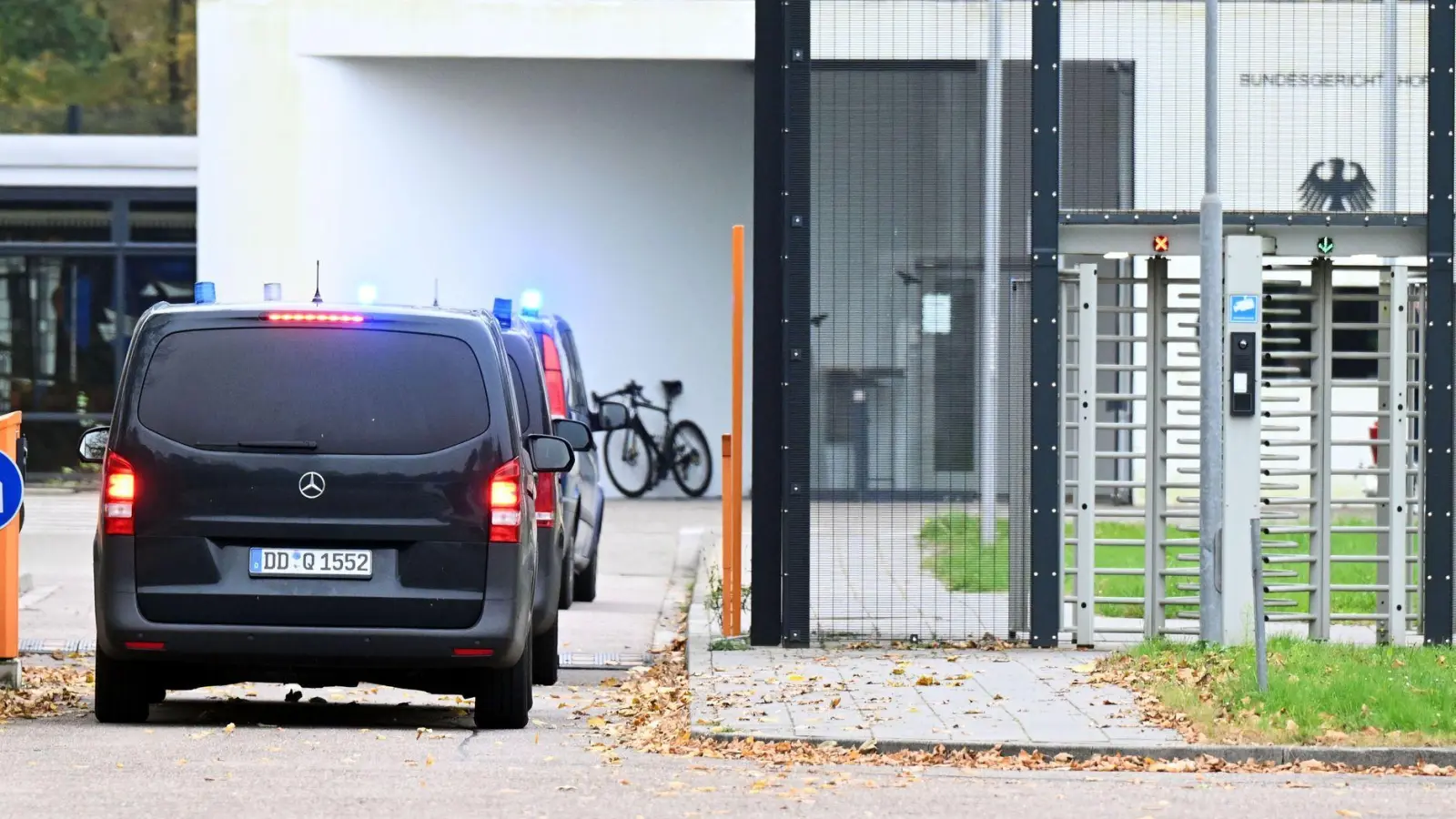 Mit eingeschaltetem Blaulicht fahren mehrere Wagen auf den Hof an der Außenstelle des Bundesgerichtshofs.  (Foto: Uli Deck/dpa)