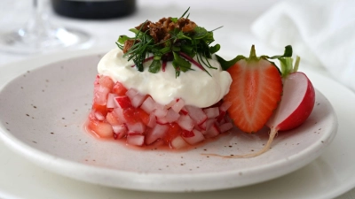 Der Erdbeer-Radieschen-Salat wird mit einem Servierring in Form gebracht. Darauf gibt es als Topping Ziegen-Feta-Creme, Kräutersalat und geröstete Krümel vom Schwarzbrot. Serviert wird er mit einem alkoholfreien Rosé. (Foto: Julia Uehren/Deutsches Wein-Institut/dpa-tmn)