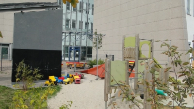 Klettergeräte, Rutsche und Sandspielzeug vor schicker Fassade: Der TIZ-Kids-Kindergarten im Erdgeschoss des Technologiezentrums. (Foto: Winfried Vennemann)