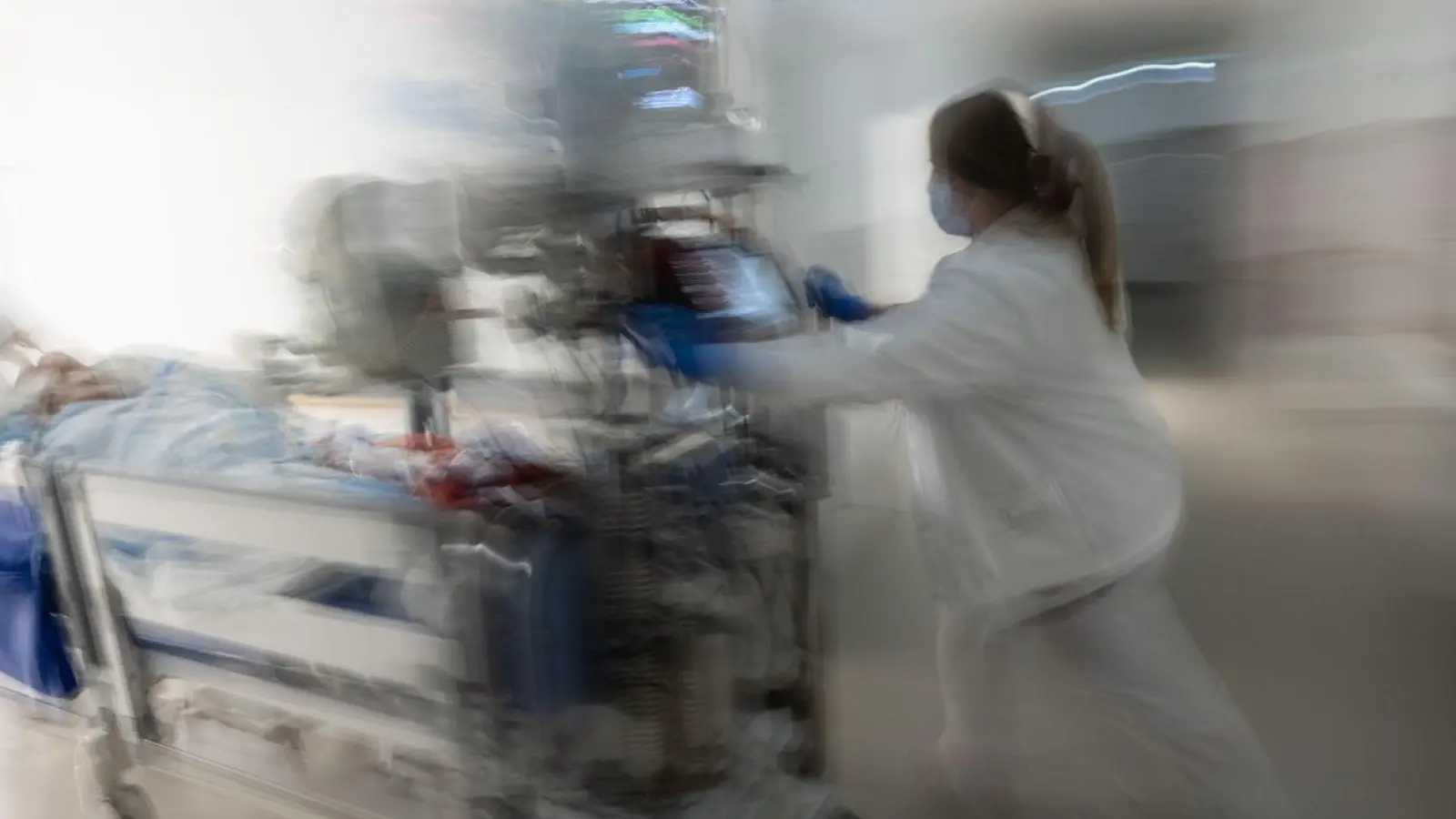 Eine Pflegerin fährt eine Intensivpatientin in einem Krankenbett durch einen Gang einer Klinik. (Foto: Marijan Murat/dpa)