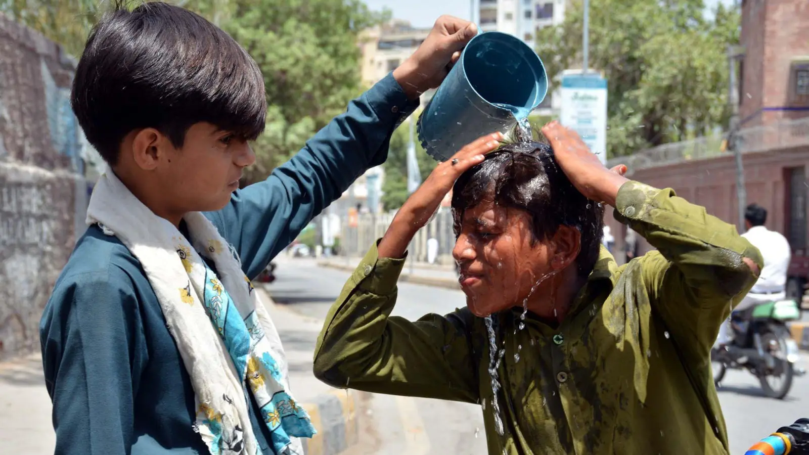 Ein Junge wäscht sich in Pakistan den Kopf, um sich an einem heißen Sommertag abzukühlen. (Foto: Ppi/PPI via ZUMA Press Wire/dpa)