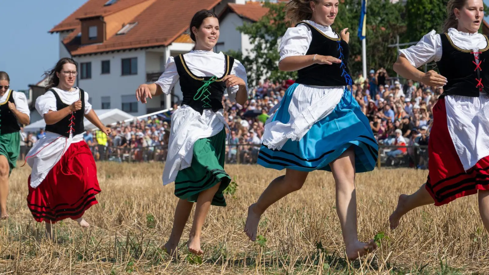 Mit wehenden Dirndln laufen junge Frauen in Markgröningen (Baden-Württemberg) beim historischen Schäferlauf barfuß auf dem Stoppelfeld. (Foto: Stefan Puchner/dpa)