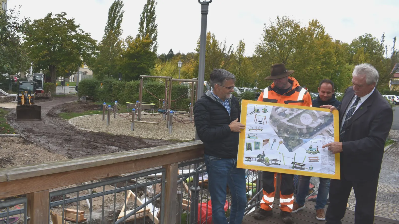 Gerald Schorr, Frieder Lunz, Frank Maes und Klaus Meier hatten zum Termin am inklusiven Spielplatz an der Jean-Paul-Allee auch einen Plan mitgebracht. Dieser zeigt, wo die Geräte platziert werden sollen. (Foto: Ute Niephaus)