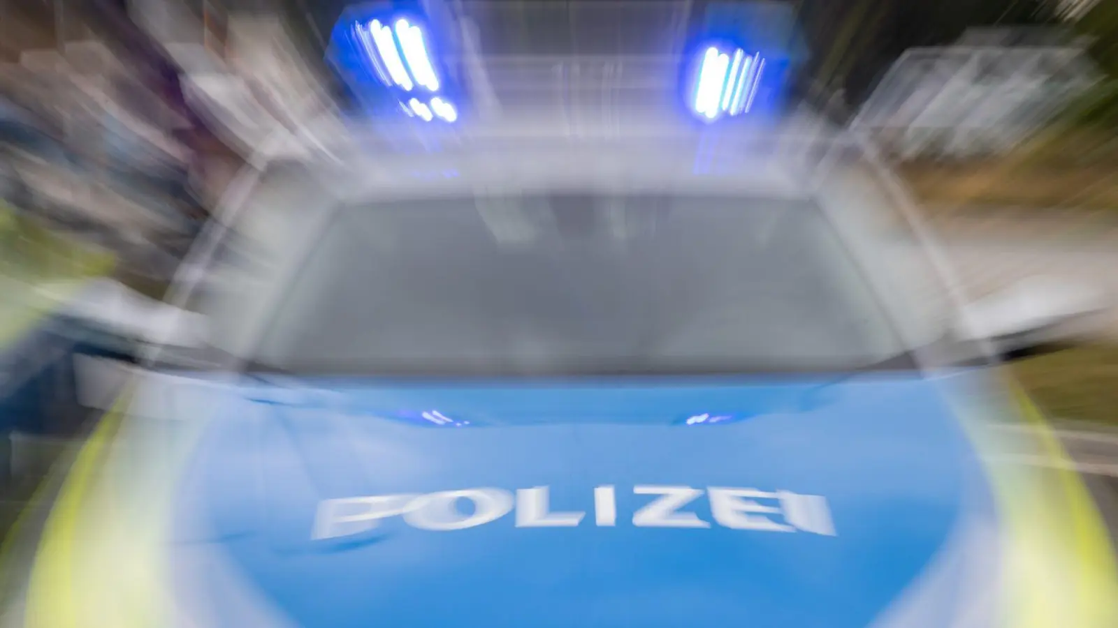 Ein Streifenwagen der Polizei mit eingeschaltetem Blaulicht. (Foto: Daniel Karmann/dpa/Symbolbild)