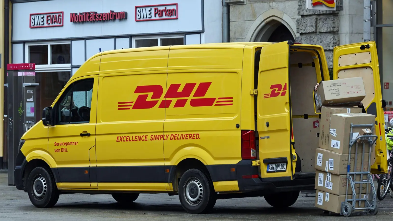 Ein Zustellfahrzeug von DHL steht an einer Straße. Der Bonner Logistiker hat in seinem Stammgeschäft - der Brief- und Paketbeförderung in Deutschland - bessere Geschäfte gemacht. (Foto: Martin Schutt/dpa)