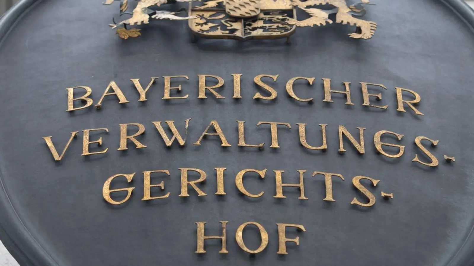 Ein Metallschild mit der Aufschrift „Bayerischer Verwaltungsgerichtshof“ hängt an der Fassade des bayerischen Verwaltungsgerichtshofs. (Foto: Peter Kneffel/dpa/Archivbild)