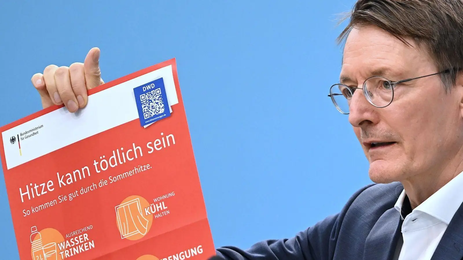 Bundesgesundheitsminister Karl Lauterbach (SPD) hält ein Plakat zum Thema Hitzeschutz hoch. (Foto: Britta Pedersen/dpa)