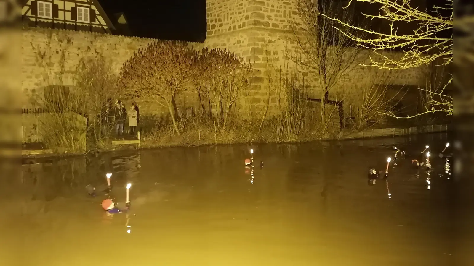 Vor Dinkelsbühls Stadtmauer als imposanter Kulisse: Bei einer Wassertemperatur um die sechs Grad legten die Fackel-Schwimmer rund einen Kilometer in der Wörnitz zurück. (Foto: Friedrich Zinnecker)