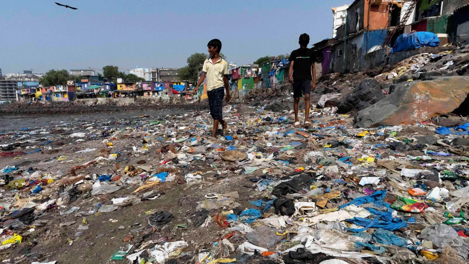 Menschen spazieren am Strand des Badhwar Park im indischen Mumbai an Plastikmüll vorbei. (Archivbild) (Foto: Rajanish Kakade/AP/dpa)