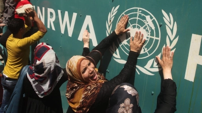 Palästinenserinnen vor UNRWA-Schild (Archivbild) (Foto: Ashraf Amra/APA Images via ZUMA Wire/dpa)