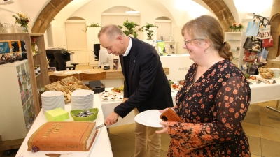 Oberbürgermeister Thomas Deffner beim Anschneiden der Geburtstagstorte in Buchform zusammen mit der Leiterin der Ansbacher Stadtbücherei, Stephanie Heinrich. (Foto: Alexander Biernoth)