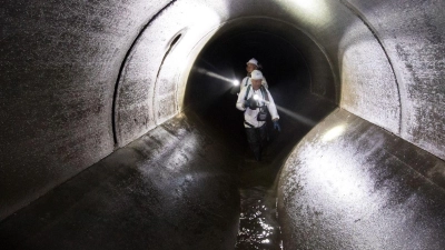 Kanalarbeiter begehen während eines Kontrollgangs die unterirdische Kanalisation. (Foto: Daniel Karmann/dpa)