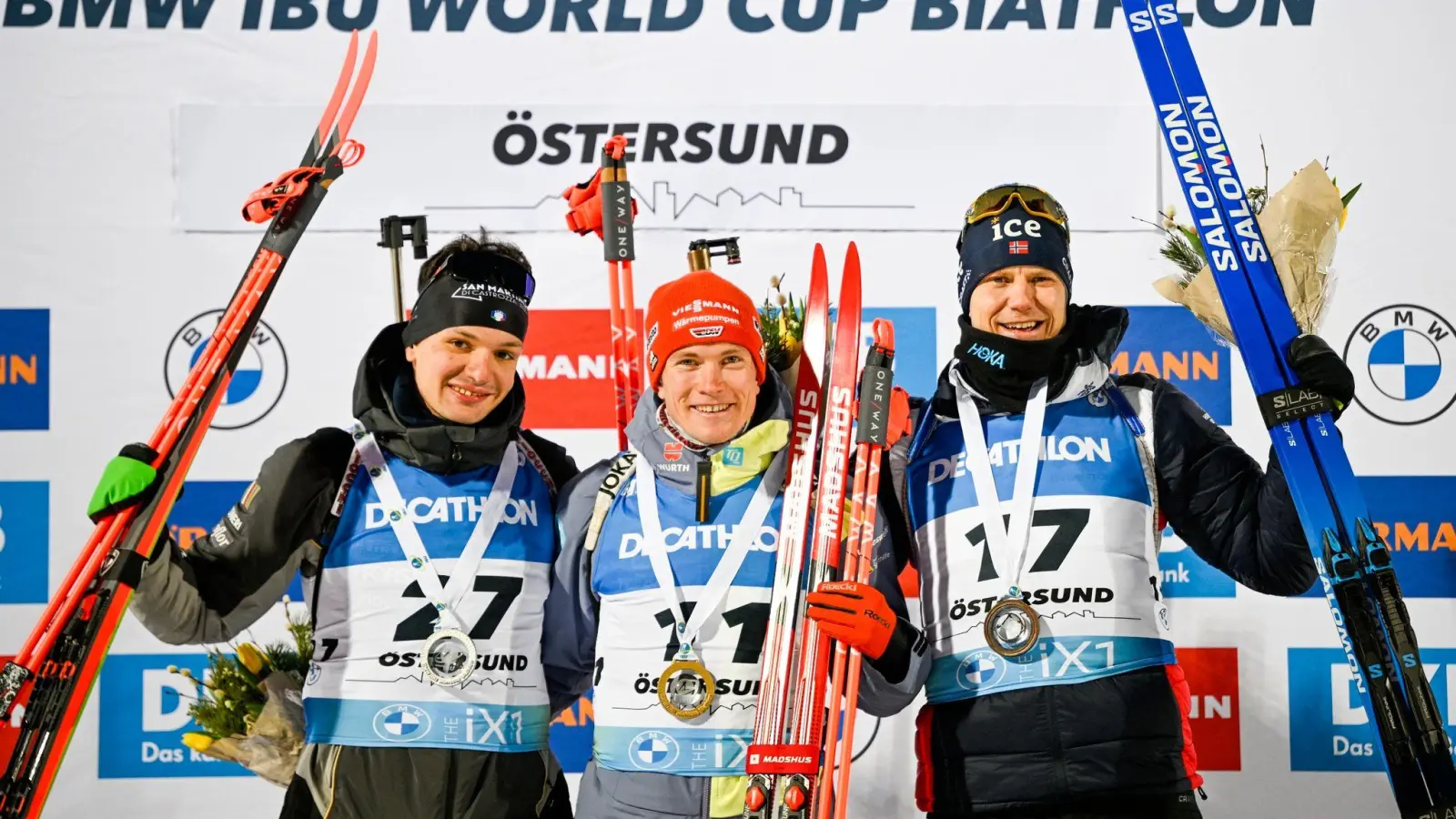 Benedikt Doll (M) feiert auf dem Podium seinen Sieg. Daneben: Tommaso Giacomel (l), Zweitplatzierter aus Italien, und Vetle Sjastad Christiansen, Drittplatzierter aus Schweden. (Foto: Anders Wiklund/TT News Agency/AP/dpa)