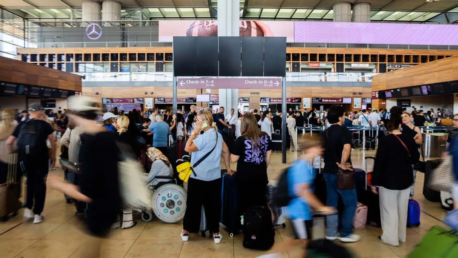 Zahlreiche Fluggäste warten am Hauptstadtflughafen BER vor einer schwarzen Anzeigetafel. Am BER ist der Flugverkehr zeitweise eingestellt worden. Grund dafür sind technische Probleme. (Foto: Christoph Soeder/dpa)