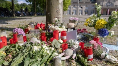 Blumen, Kerzen und handgeschriebene Trauerbekundungen an einem Baum im Kurpark Bad Oeynhausen. (Foto: Str/dpa)