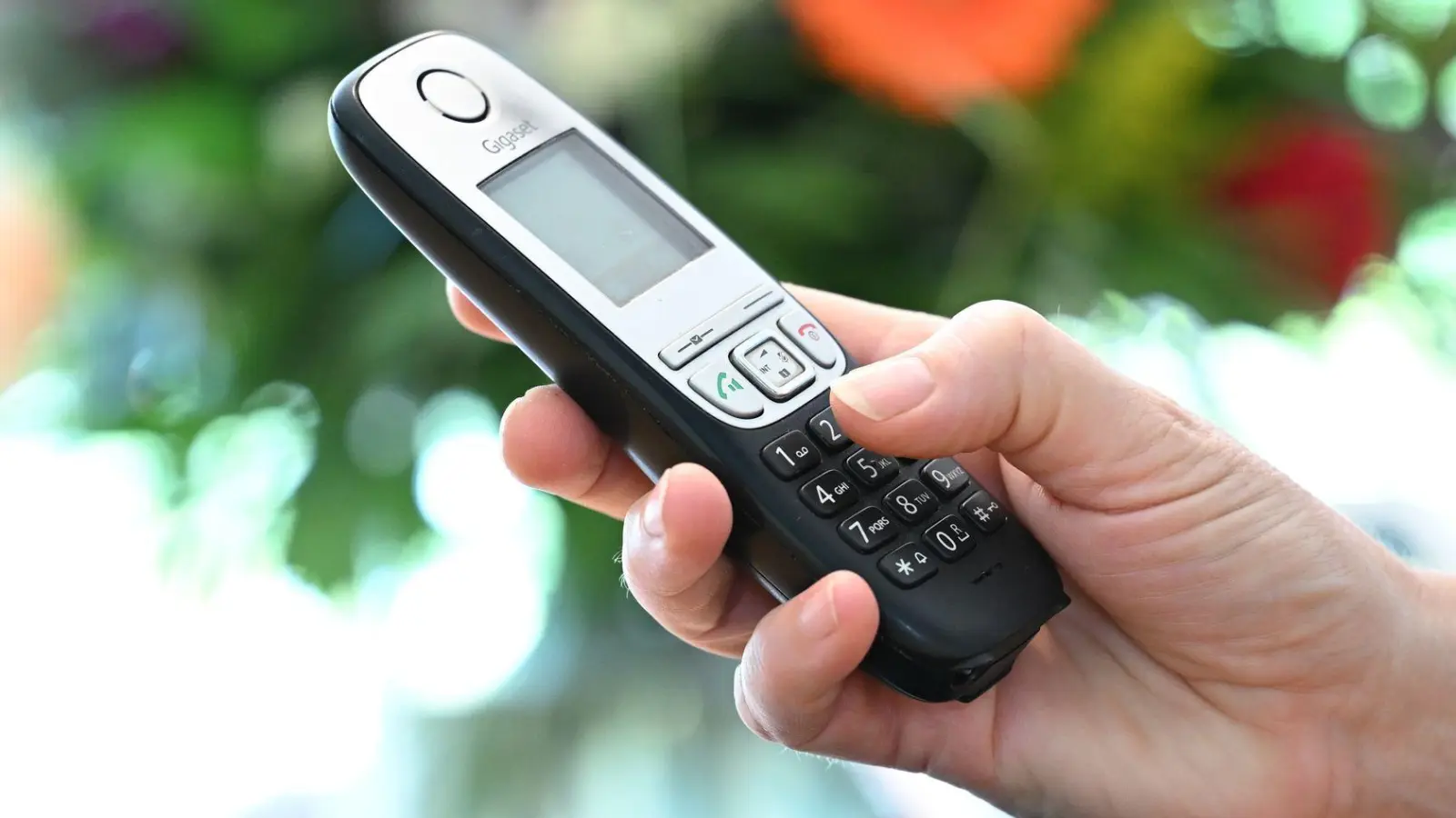 ILLUSTRATION - Eine Frau hölt ein Festnetz-Telefon in ihrer Hand.  (Foto: Bernd Weissbrod/dpa)