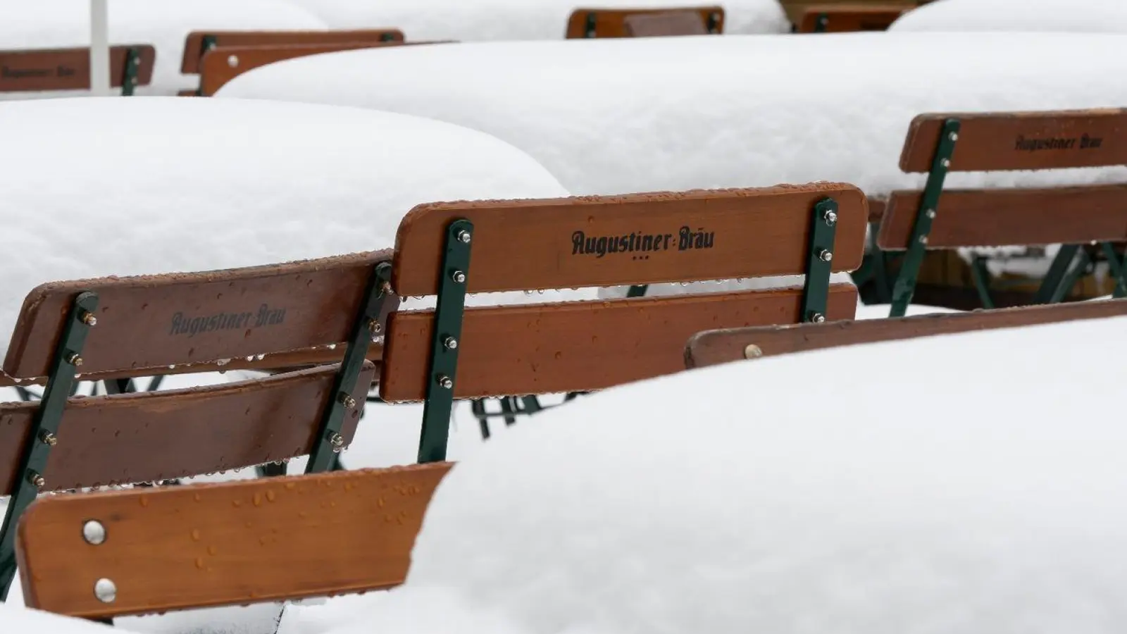 Schnee liegt auf Tischen und Stühlen in einem Biergarten am Walchensee. (Foto: Peter Kneffel/dpa)