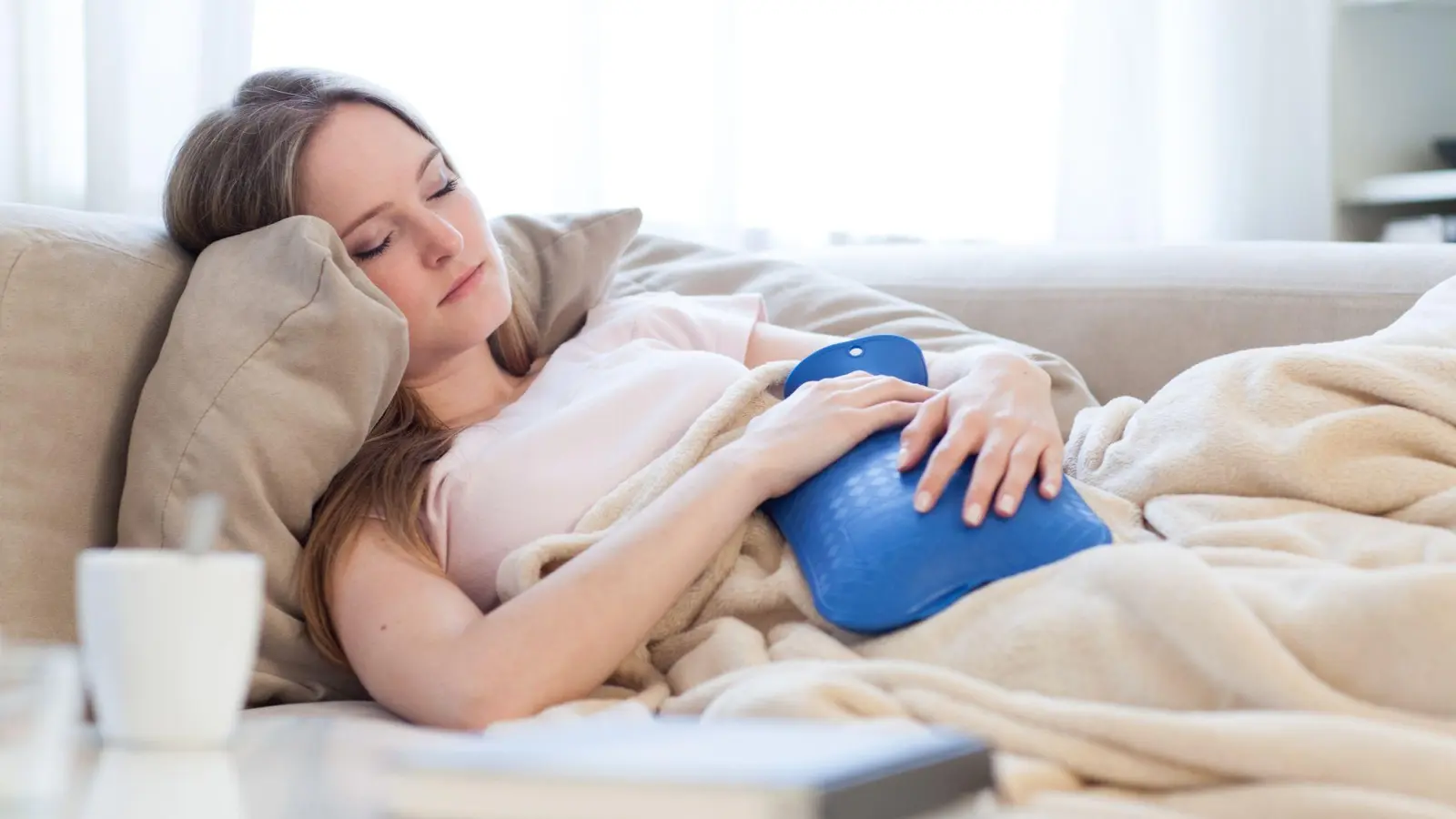 Krämpfe, Übelkeit, Durchfall. Die Symptome, die Frauen während ihrer Menstruation spüren, können variieren. Oftmals hilft es aber, sich auf der Couch mit einer Wärmflasche auszuruhen. (Foto: Christin Klose/dpa-tmn)