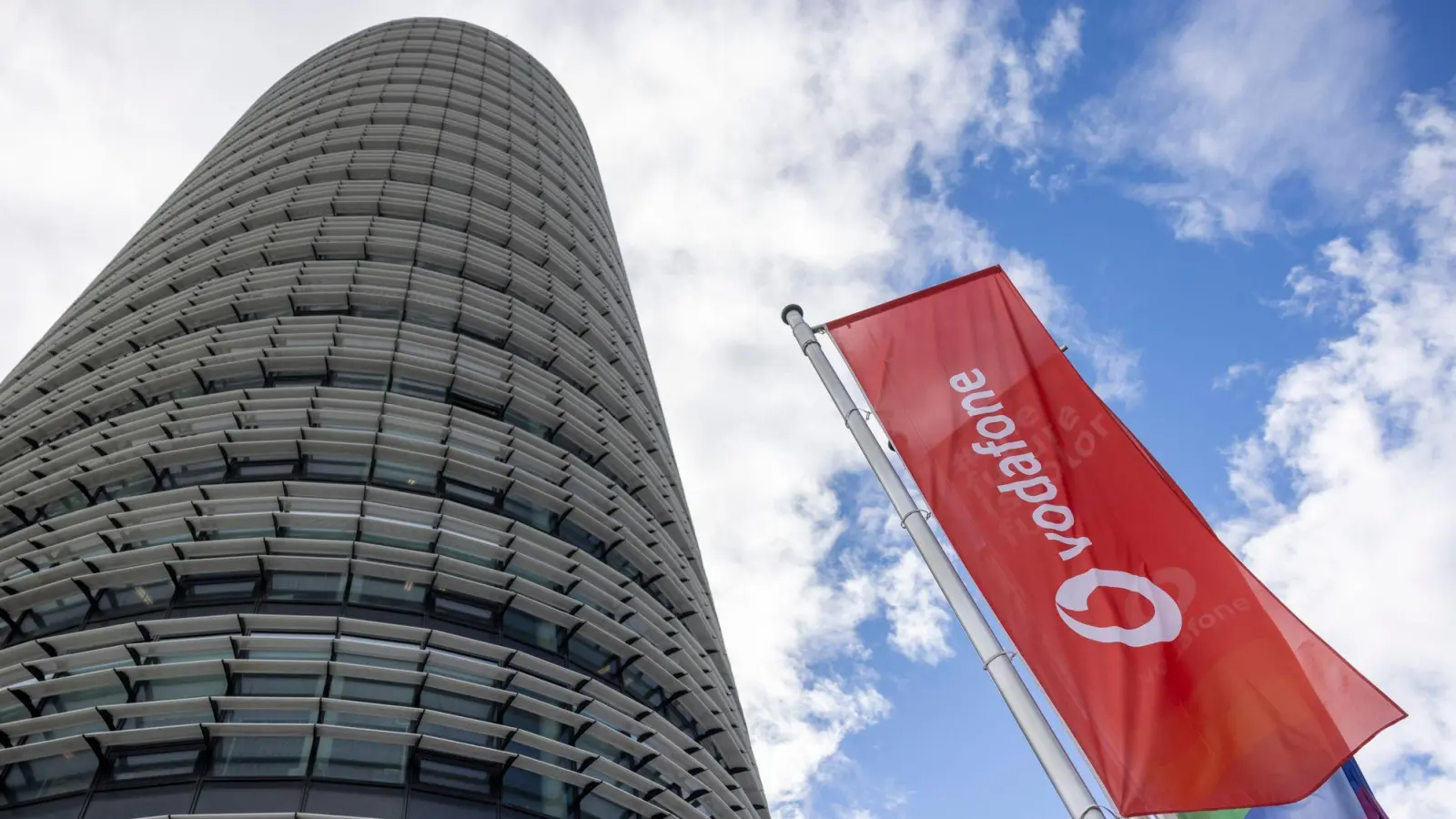 Vodafone-Flaggen wehen vor der Firmenzentrale in Düsseldorf. Der Telekommunikationsanbieter hat ein insgesamt schwaches Quartal hinter sich. (Foto: Thomas Banneyer/dpa)