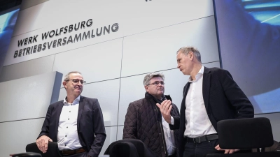 Konzernchef Oliver Blume (r.) berät sich vor seiner Rede mit  VW-Verhandlungsführer Arne Meiswinke (Mitte). (Foto: Ronny Hartmann/POOL/dpa)