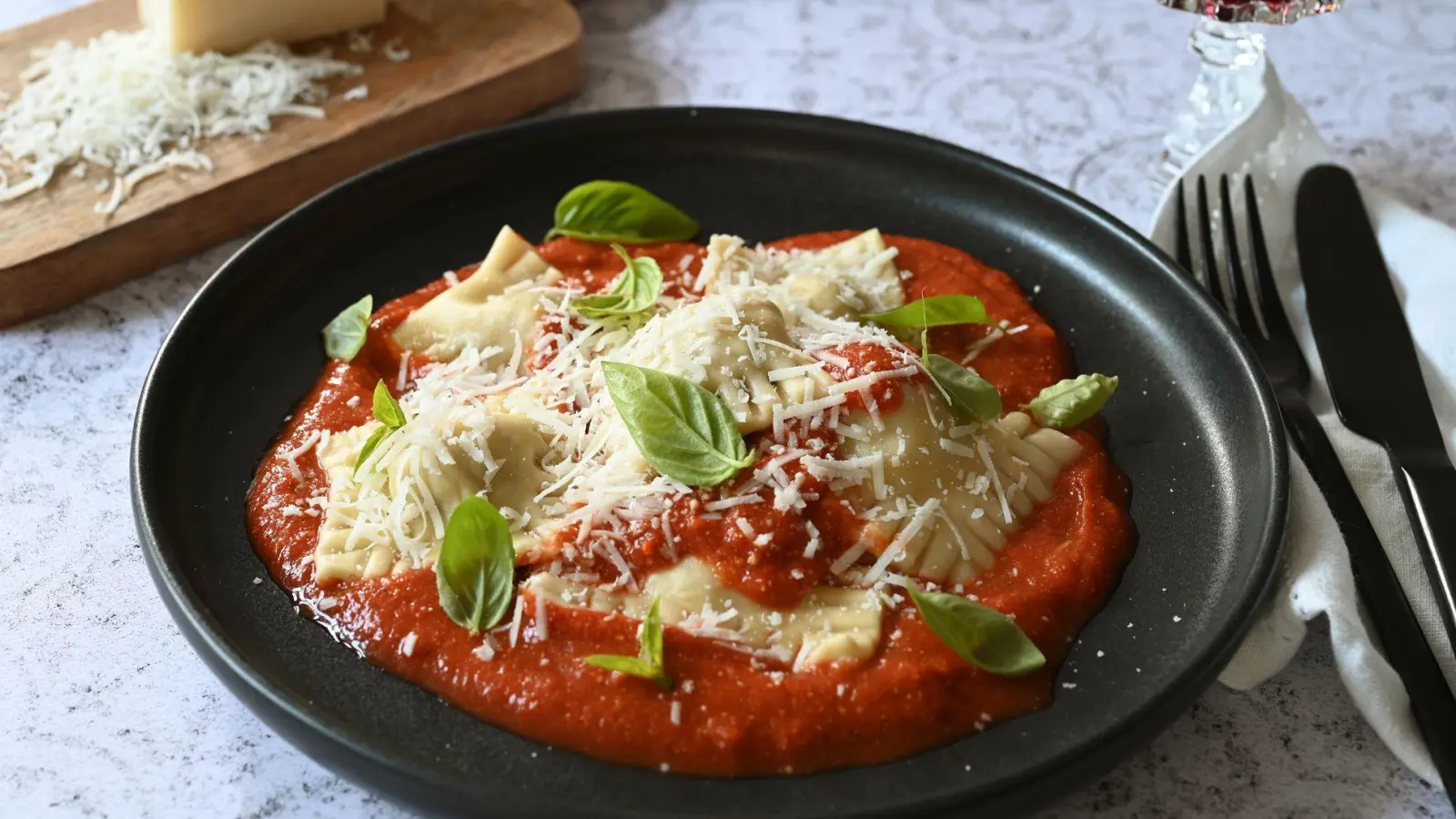 Kein Mischmasch: Die selbstgemachten Ravioli thronen beim Servieren auf der Tomatensoße.  Basilikumblätter sorgen für einen Farbtupfer. (Foto: Julia Uehren/loeffelgenuss.de/dpa-tmn)