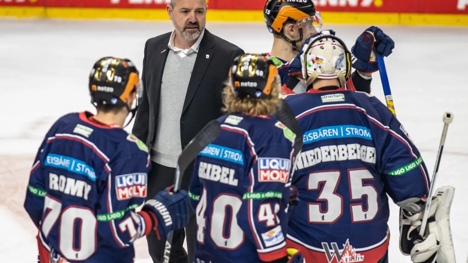 Berlins Cheftrainer Serge Aubin (2.v.l) unterhält sich nach einem Spiel mit seinen Spielern auf dem Eis. (Foto: Andreas Gora/dpa)