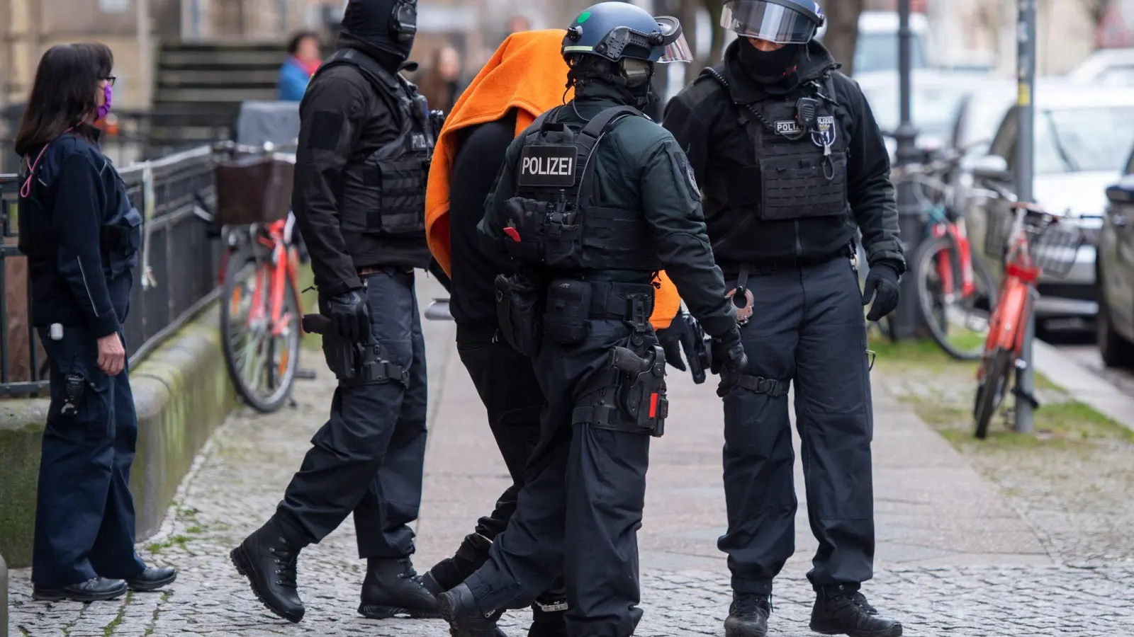 Polizisten bringen den Angeklagten unter einer Decke aus dem Gerichtsgebäude in Berlin. (Foto: Christophe Gateau/dpa)