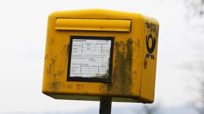 Ein Briefkasten der Deutschen Post steht auf einer Wiese am Rand einer Siedlung im Bergischen Land (NRW).  (Foto: Oliver Berg/dpa)