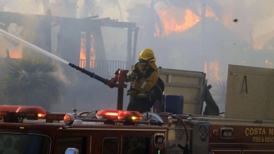 Der Feuerwehrmann Nick Cerciello vom Costa Mesa Fire Department löscht ein Haus, das während eines Lauffeuers in Brand geraten ist. (Foto: Ruaridh Stewart/ZUMA Press Wire/dpa)