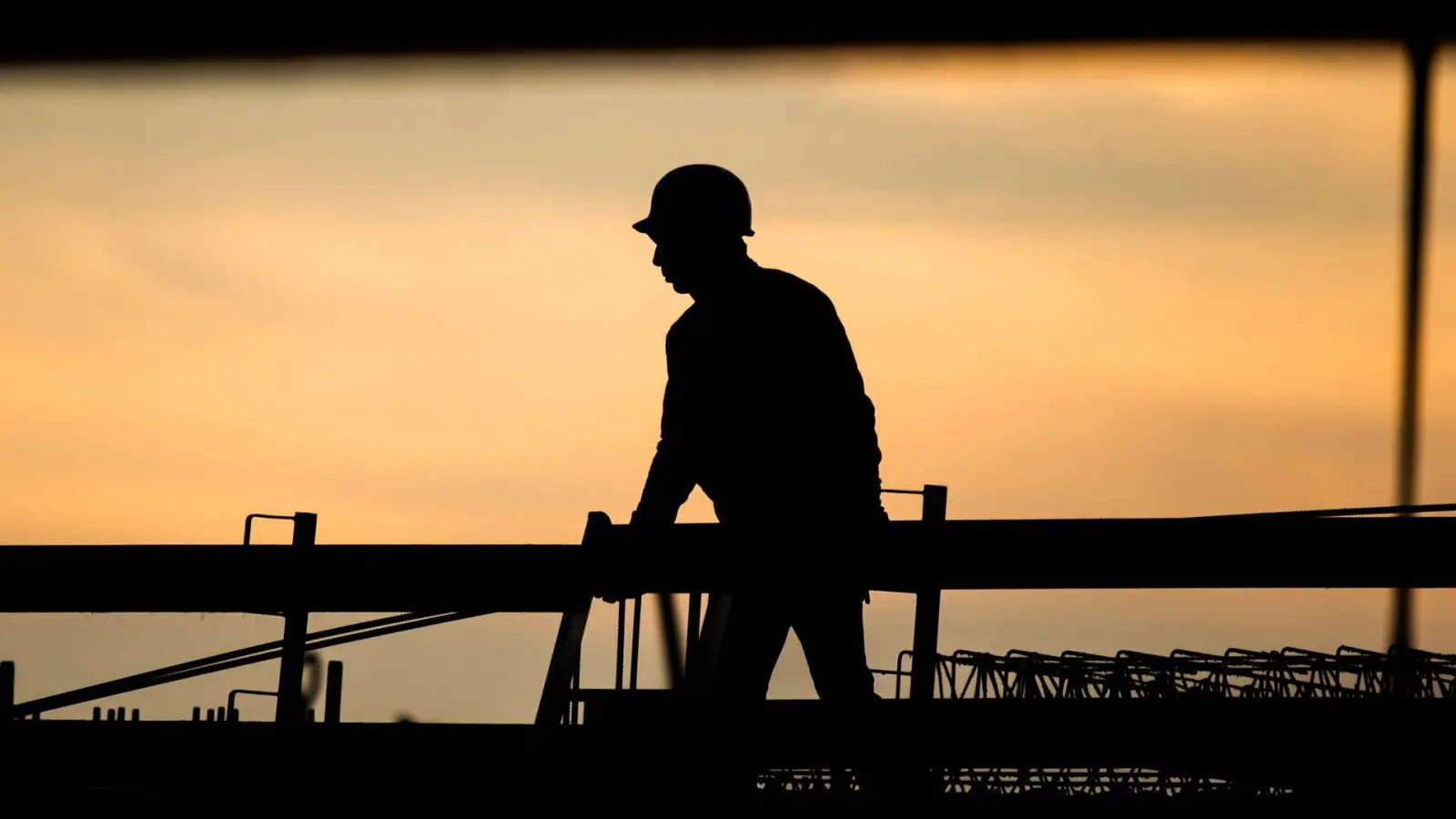 Ein Bauarbeiter in der Morgendämmerung. Laut Ifo-Beschäftigungsbarometer wollen viele Unternehmen Personal abbauen, in der Baubranche zeichnet sich jedoch keine größere Entlassungswelle ab. (Foto: Julian Stratenschulte/dpa)