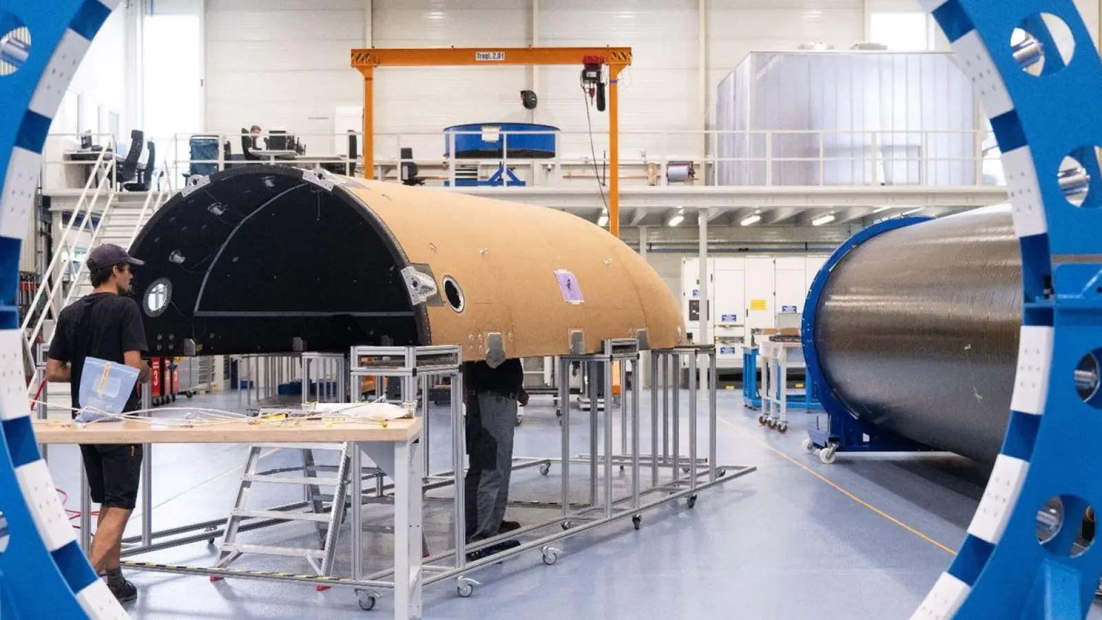 Mitarbeiter des Raumfahrtunternehmens Isar Aerospace fertigen in einer Halle die Verkleidung einer Rakete. (Foto: Marijan Murat/dpa/Archivbild)