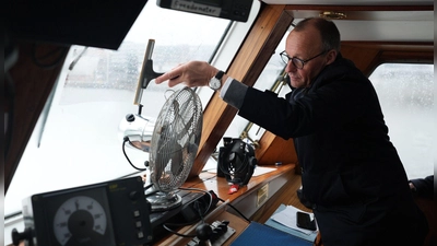 Scheibenwischer: Friedrich Merz, Kanzlerkandidat und Parteivorsitzender der CDU, wischt die Windschutzscheibe während der Fahrt mit einer Barkasse im Hamburger Hafen sauber. (Foto: Marcus Brandt/dpa Pool/dpa)