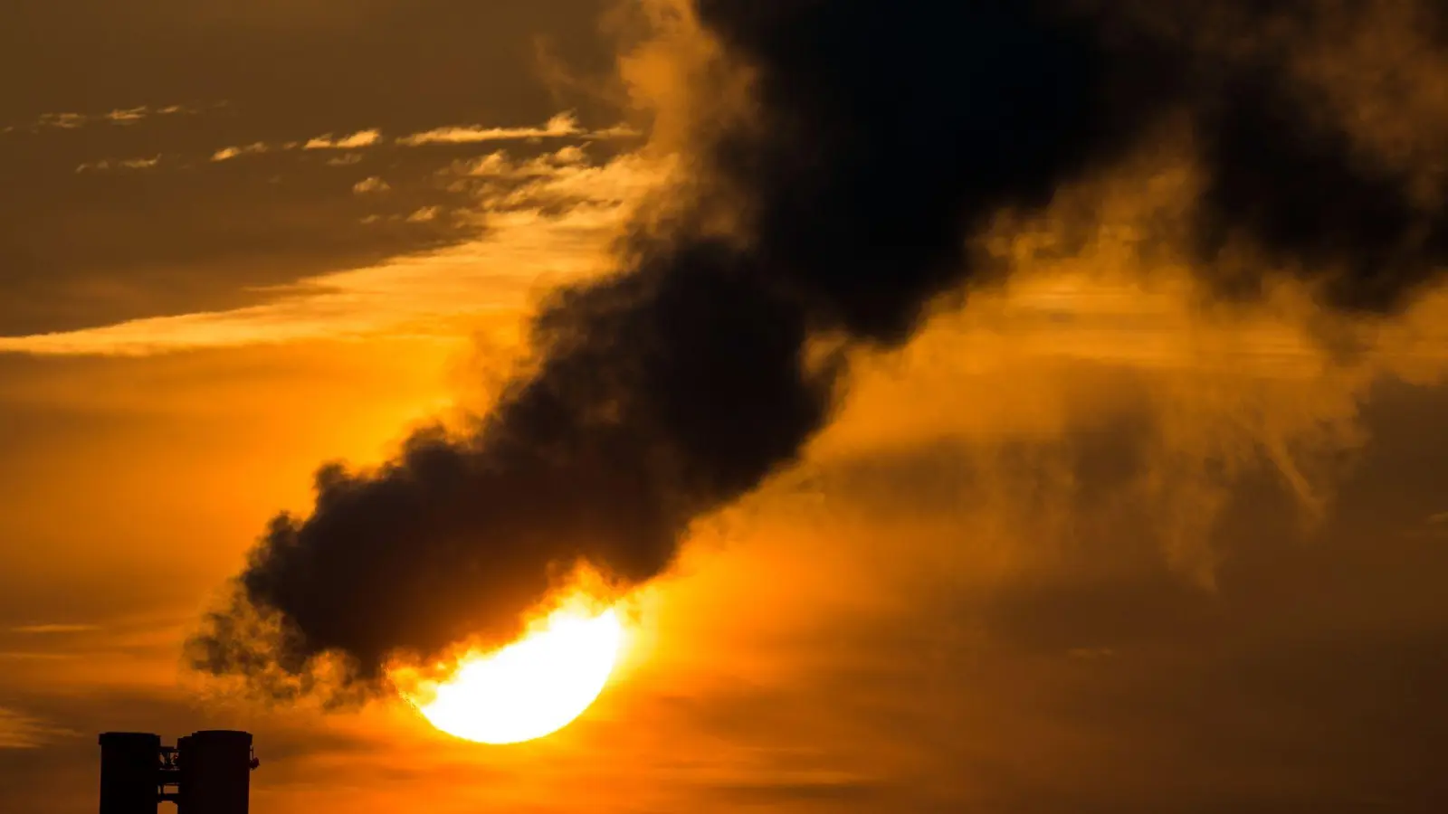 Die Morgensonne scheint hinter qualmenden Schornsteinen eines Blockheizkraftwerks in Frankfurt (Oder) (Brandenburg). (Foto: picture alliance / dpa)