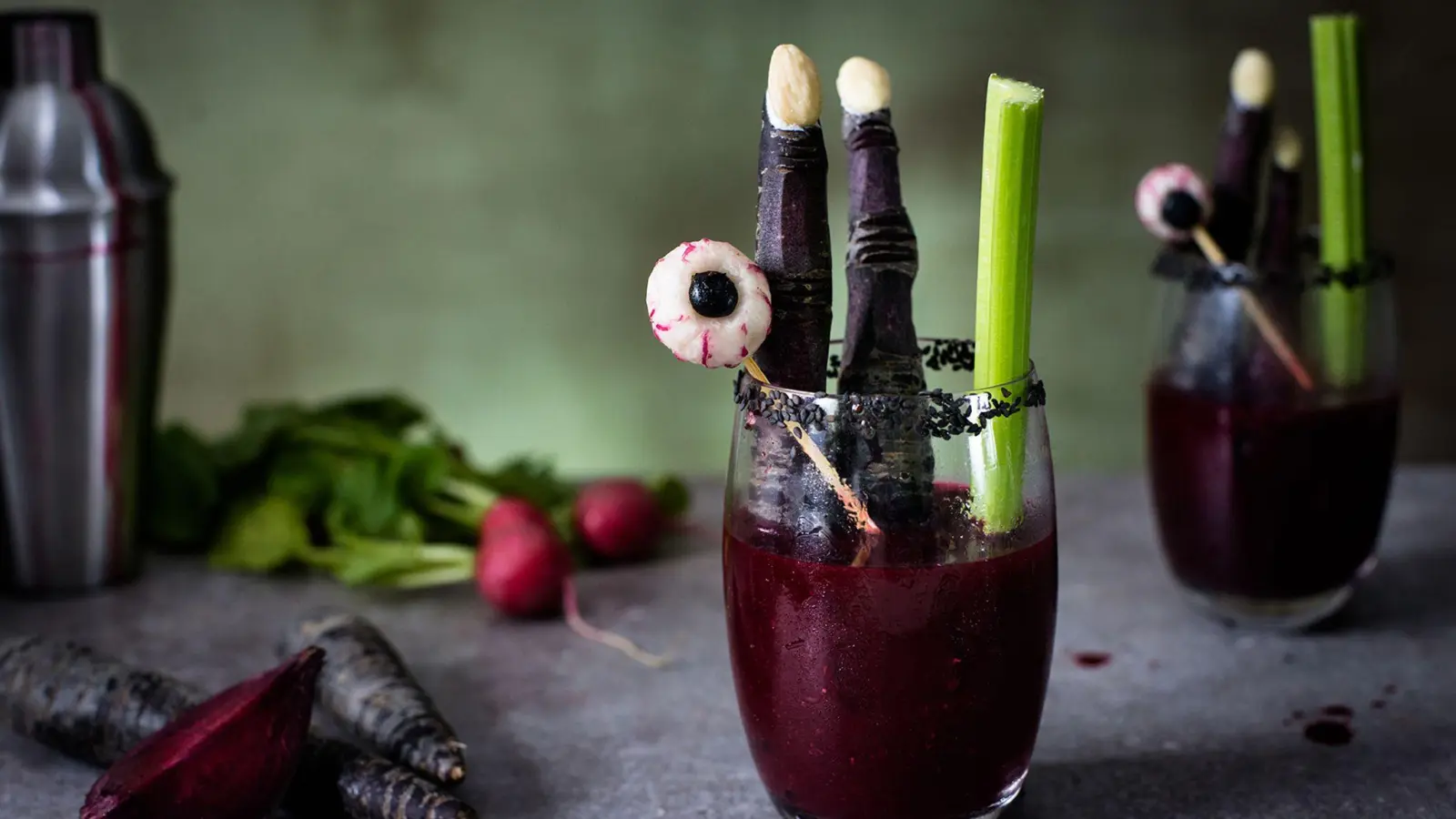 Zu Fingern geschnitzte lila Möhren und Glubschaugen aus Radieschen und Blaubeeren geben der Bloody Mary einen schaurig-schönen Touch. (Foto: BVEO/dpa-tmn)