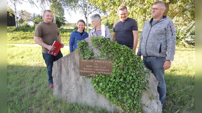 Die Dorfgemeinschaft von Aichau plant den Bau einer Kapelle oberhalb der Böschung im Hintergrund. Das Projekt stellten jetzt Felix Gundacker, Tamara Perske und Edith Geißler sowie Daniel und Martin Gögelein vor, die unser Bild (von links) am Stein zur Erinnerung an die Flurbereinigung zeigt. Auf diesem steht die weiße Kerze, die ihren endgültigen Platz im Innern des Gotteshauses finden soll. (Foto: Peter Zumach)