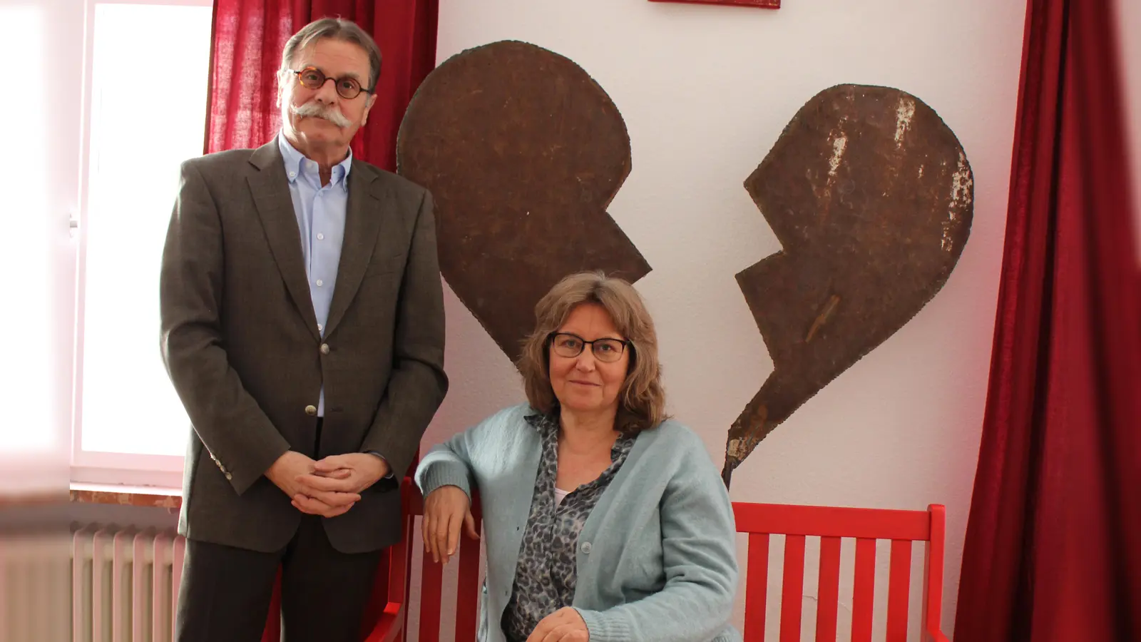 Dr. Eckhard Göritz, Vorsitzender des Ansbacher Vereins Rauhreif, und die Sozialpädagogin Christine Schwab, die auf einer roten Bank als Symbol gegen sexualisierte Gewalt sitzt, bangen um die Zukunft der Ansbacher Beratungsstelle. (Foto: Kristina Schmidl)