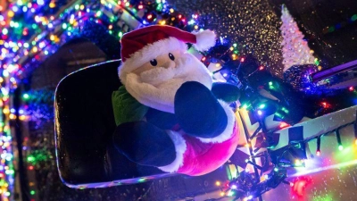 Eine Weihnachtsmann-Figur hängt an einem mit Lichterketten geschmückten Fahrzeug am Georgsplatz in Hannover. (Foto: Michael Matthey/dpa)