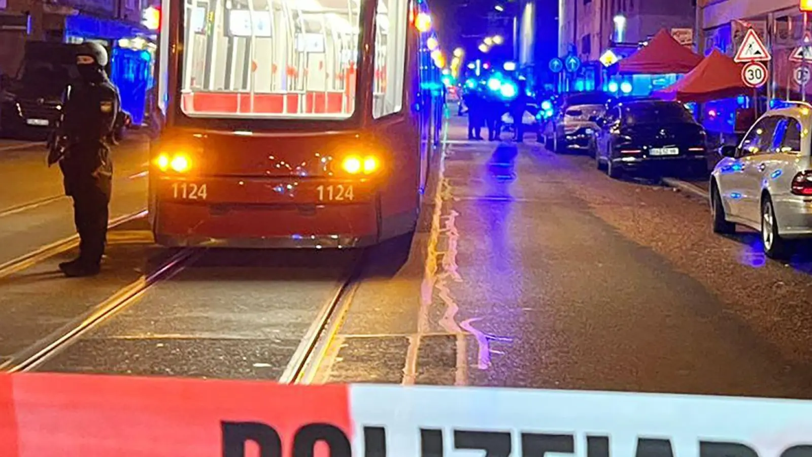 Ein Polizist steht mit einer Maschinenpistole neben einer Straßenbahn hinter einer Polizeiabsperrung. Bei Schüssen in der Nürnberger Südstadt war Ende Oktober 2022 ein Mann gestorben und ein weiterer schwer verletzt worden. (Foto: Eberlein/vifogra/dpa)