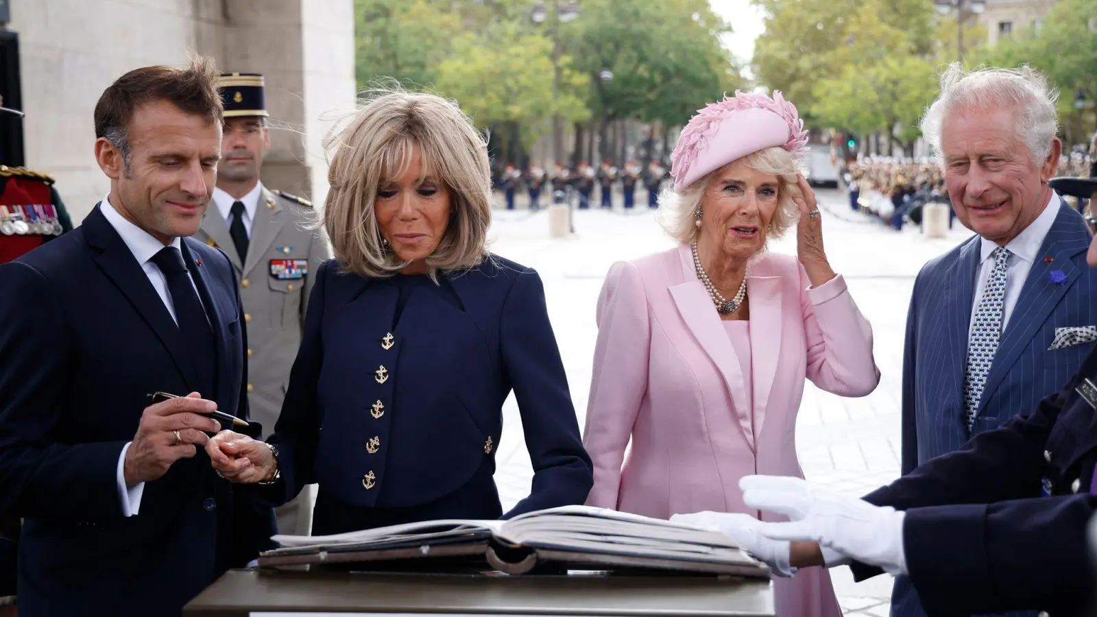 Präsident Emmanuel Macron (l-r) und und seine Ehefrau Brigitte Macron sowie Königin Camilla und König Charles III. von Großbritannien tragen sich während einer Zeremonie am Triumphbogen in Paris ins Goldene Buch ein. (Foto: Yoan Valat/EPA POOL/AP/dpa)